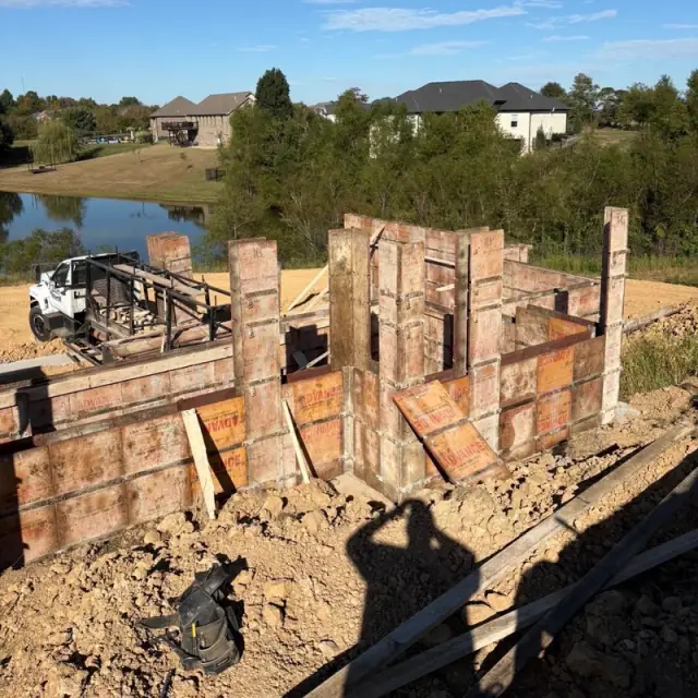 Steel wall forms for a basement, with a work truck and a pond behind