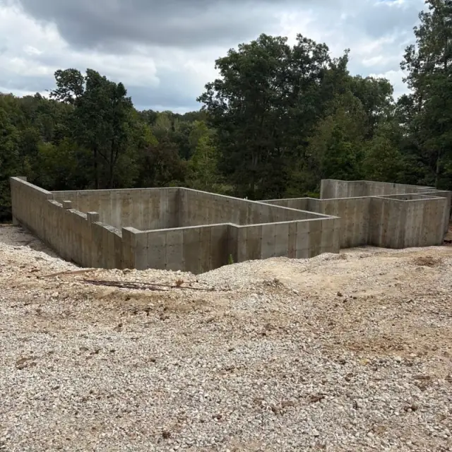 Finished poured concrete foundation walls on a gravel lot in the woods