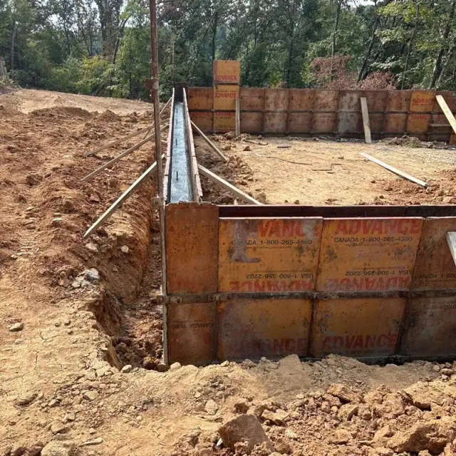 A freshly poured narrow form beside a run of steel wall forms